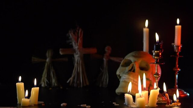 Old Skull and candle with incense on old altar plate which has dim light. Select focus, black background. Straw voodoo dolls. Copy space