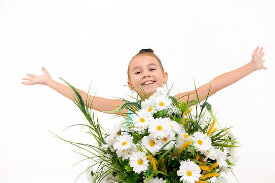 Girl in summer dress in the studio with white background during photo shoot with white flowers daisies