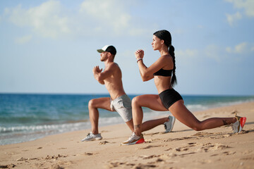 Healthy lifestyle. Young beautiful couple doing sports exercises at the beach.