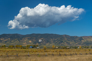 Large white cloud over a hilly ridge