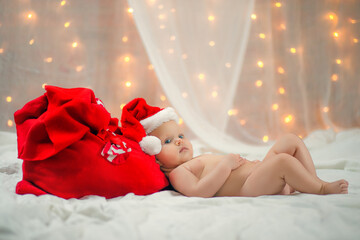 Fototapeta na wymiar Beautiful little baby liyng with Santa Claus red bag on bed. New Year's holidays.