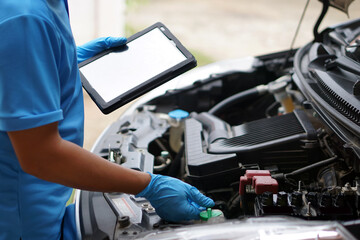 Mechanic is checking car engine, use smart tablet to record and diagnose the problems of engine        Concept : using technology to manage car engine. Car service and maintenance.   