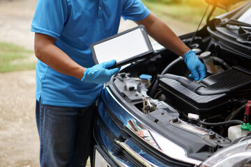 Mechanic is checking car engine, use smart tablet to record and diagnose the problems of engine        Concept : using technology to manage car engine. Car service and maintenance.     