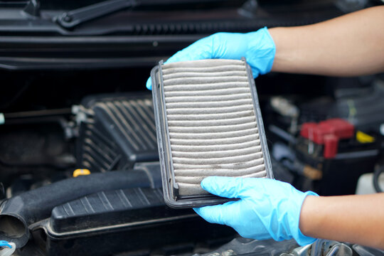 Mechanic's hands hold dusty and dirty air filter pad of car. Concept: checking and maintenance machine, car engine.
