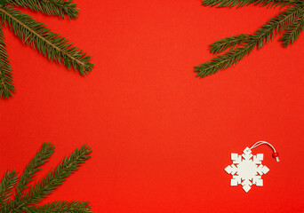 Branches of the Christmas tree and decoration of the Christmas tree in the form of snowflakes on a red background. Christmas concept