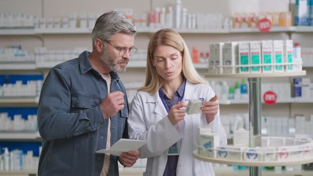 Handsome caucasian man in glasses consulting with doctor, talking to pharmacist getting advice and medical prescription. Medicine and healthcare. Pharmacy store. - Powered by Adobe