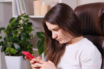 The woman looks at the screen of the phone, tilting her head down, tension of the muscles of the...