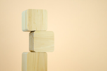 empty wooden cubes are stacked in a tower shape, one on top of other. blocks are vertically lined on beige background. concept of business, interaction, growth. Template for design, space for text