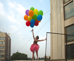 young woman stands on the street in the background of blue sky. In his hand holds a bunch of...