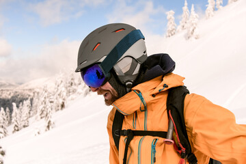 Head shot of man skier with beard wearing yellow jacket and ski helmet and goggles