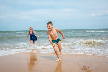 A grandmother is playing with her grandson on the beach when the wave crashes on their feet.