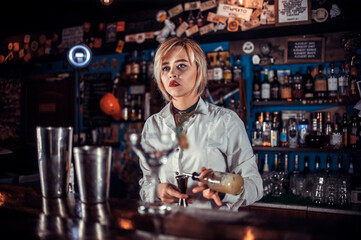 Girl barman formulates a cocktail on the taproom