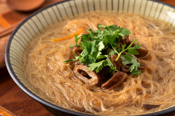 Delicious intestine vermicelli in a bowl on dark wooden table background.