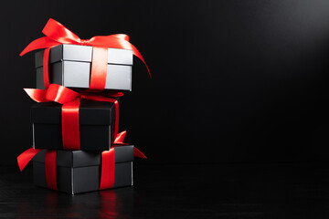 Black christmas boxes with red ribbon on black background. Black Friday and Boxing Day composition. Shopping concept.