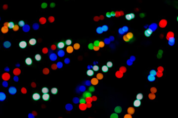 Multicolored bokeh of Christmas garlands on a Christmas tree at night on street Christmas Eve and New Years. Bright flashes of colored lights, bokeh texture. Festive colorful background. 