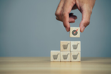 Man hands flips cube with icon target goal shopping cart symbol, sale volume increase make business grow.