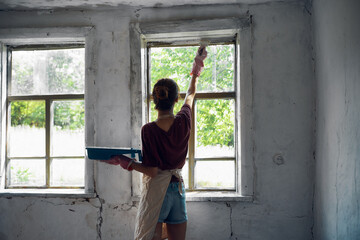 Fototapeta na wymiar woman paints house renovation interior room painter