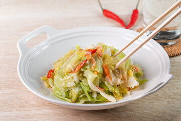 Stir-fried cabbage with sergestid Sakura shrimp in white plate on wooden table background.