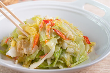 Stir-fried cabbage with sergestid Sakura shrimp in white plate on wooden table background.