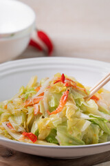 Stir-fried cabbage with sergestid Sakura shrimp in white plate on wooden table background.