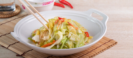 Stir-fried cabbage with sergestid Sakura shrimp in white plate on wooden table background.