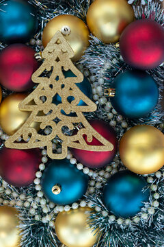 vertical photo with christmas or new year background with red, golden and blue christmas balls, golden beads and sparkling golden christmas tree. top view