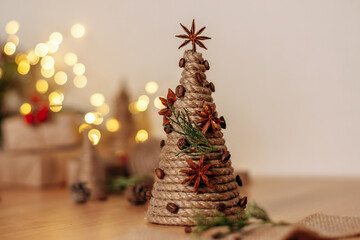 A creative handmade Christmas tree made of a cardboard cone, wrapped with rope and decorated with...