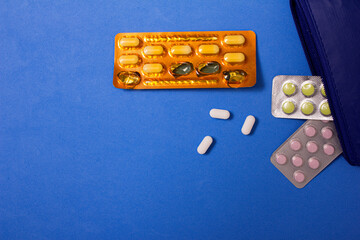 Pills on blue background coming out of a case. copy space.