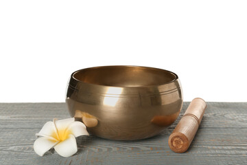 Golden singing bowl, mallet and flower on grey wooden table against white background