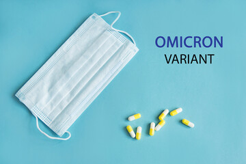 Medical protective mask and pills in capsules on a blue background with B.1.1.529 omicron variant...