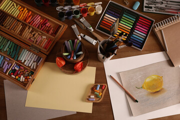 Artist's workplace with drawing, soft pastels and color pencils on table, flat lay