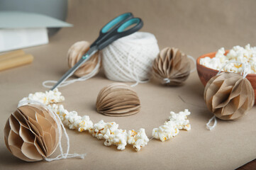 Fototapeta na wymiar Selective focus. DIY Scandinavian Nordic Craft Paper Christmas Balls and garland of popcorn. Eco friendly New Year from handmade decor...