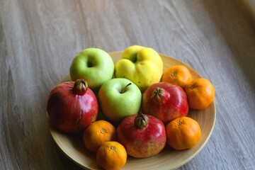 Wooden bowl filled with various seasonal fruit on a table. Selective focus.
