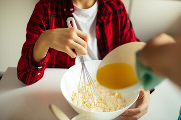 Mom and son are cooking together in kitchen. Photo of hands, unrecognizable persons, lifestyle, baking at home, hand-made baking, mixing of ingredients