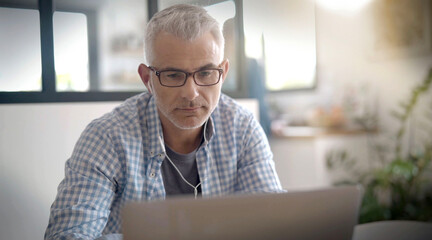 man telecommuting on his laptop at home