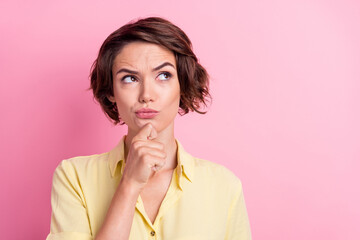 Photo of unsure millennial brunette lady look empty space wear yellow shirt isolated on pink color...