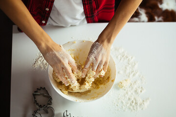 teenager's hands knead dough in bowl on table, top view. Flour, pastries. Hobbies and activities for child. Cooking at home.