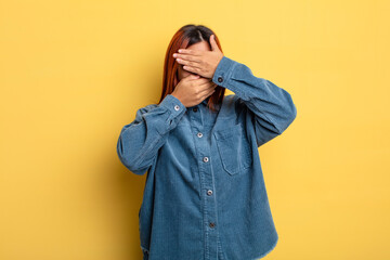 young hispanic woman covering face with both hands saying no to the camera! refusing pictures or...