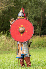 Knight soldier in armour holding red wooden shield during medieval re-enactment