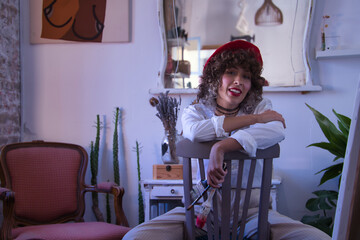 Young woman, painter, designer and artist with a red beret, sitting on a chair upside down and...