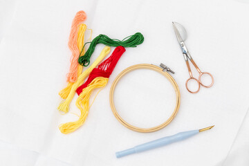 Rounded scissors, punch needle,hoop, floss and thread. Embroidery tools. Needlework