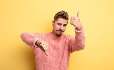 young handsome man feeling confused, clueless and unsure, weighting the good and bad in different...