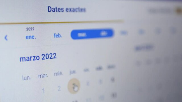 Choosing dates for travel at website calendar. Online booking vacation. "March 2022" written in spanish. 4k video