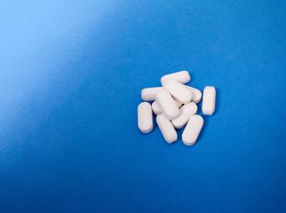 White pills on blue background. Copy space.