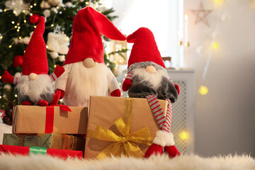 Cute Christmas gnomes and gift boxes on carpet in room