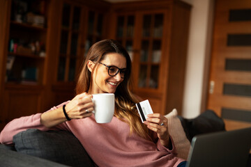 Young businesswoman at home makes a purchase on the Internet. Beautiiful woman on the laptop with credit card.