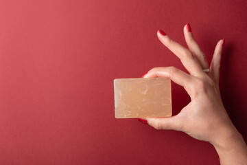 Woman hand holding soap with two fingers