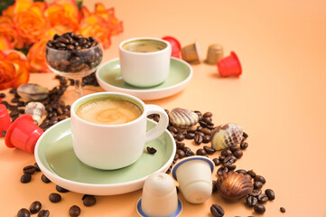 Coffee, chocolate, coffee beans and flowers. Espresso with froth or macchiato in small cups, sprinkled coffee beans and chocolates. High quality photo. Copy space