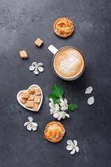 Coffee, sweets and spring flowers on dark stone background. Top view