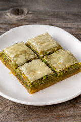 Pistachio baklava on a wooden background. Turkish style pistachio baklava presentation and service. Vertical view. close up